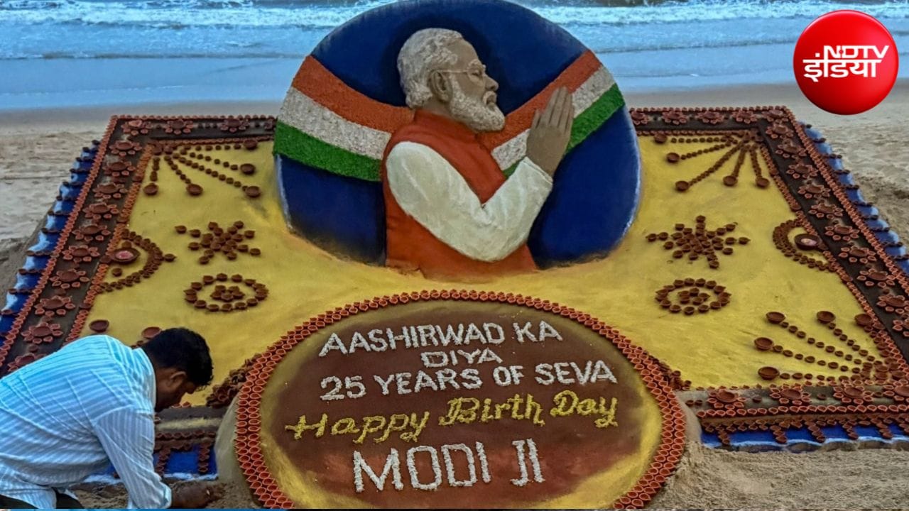 प्रधानमंत्री नरेंद्र मोदी के जन्मदिन पर ओडिशा के पुरी में समुद्र किनारे रेत से कृति बनाता एक कलाकार.