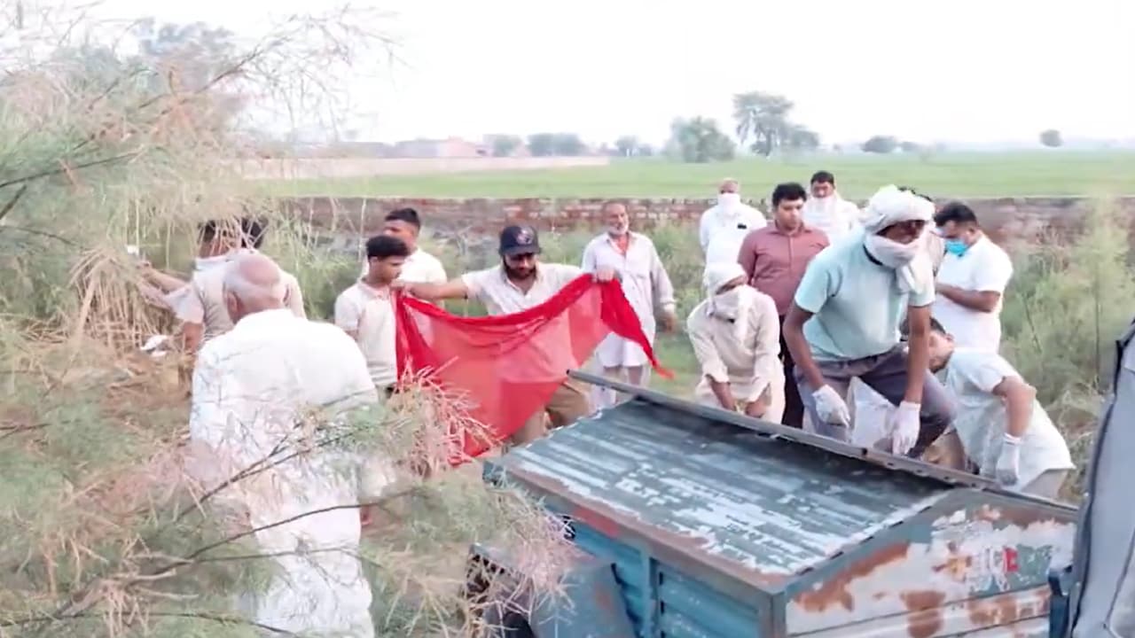कब्र से शव निकालकर ले जाती हुई पुलिस की टीम