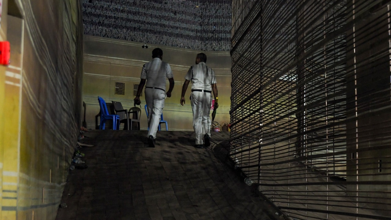 Kolkata Police personnel walk through a corridor inside a Durga Puja pandal after an exit gate collapsed, causing a stampede