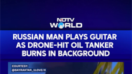 Russian Man Plays Guitar As Drone Hit Oil Tanker Burns In The Background