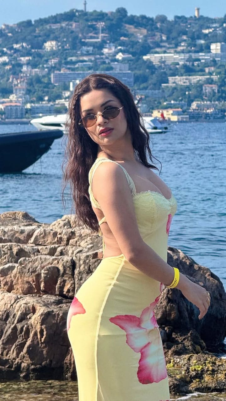The backless yellow dress features a delicate pink floral print, adding a beautiful visual contrast to her overall look.