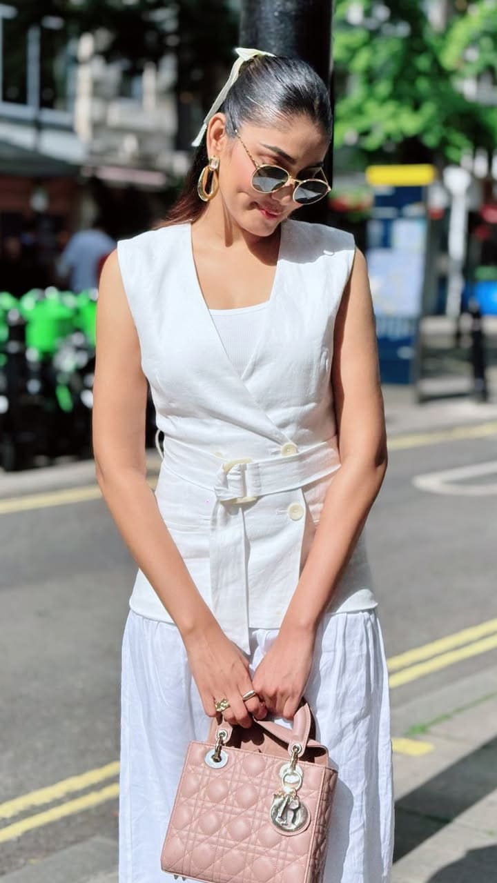 Sana Makbul exudes sophistication in a crisp linen vest and flowing skirt. The cinched waist belt adds a touch of refinement to her summer look.
