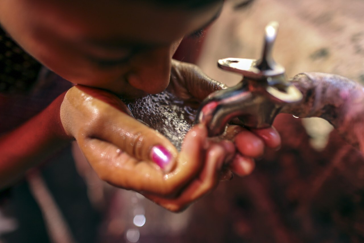 A girl drinks water from a faucet. (Photographer: Dhiraj Singh/Bloomberg)