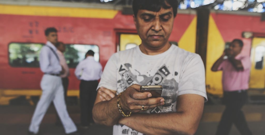 A passenger uses phone at Mumbai Central railway station in Mumbai, India (Photographer: Dhiraj Singh/Bloomberg)