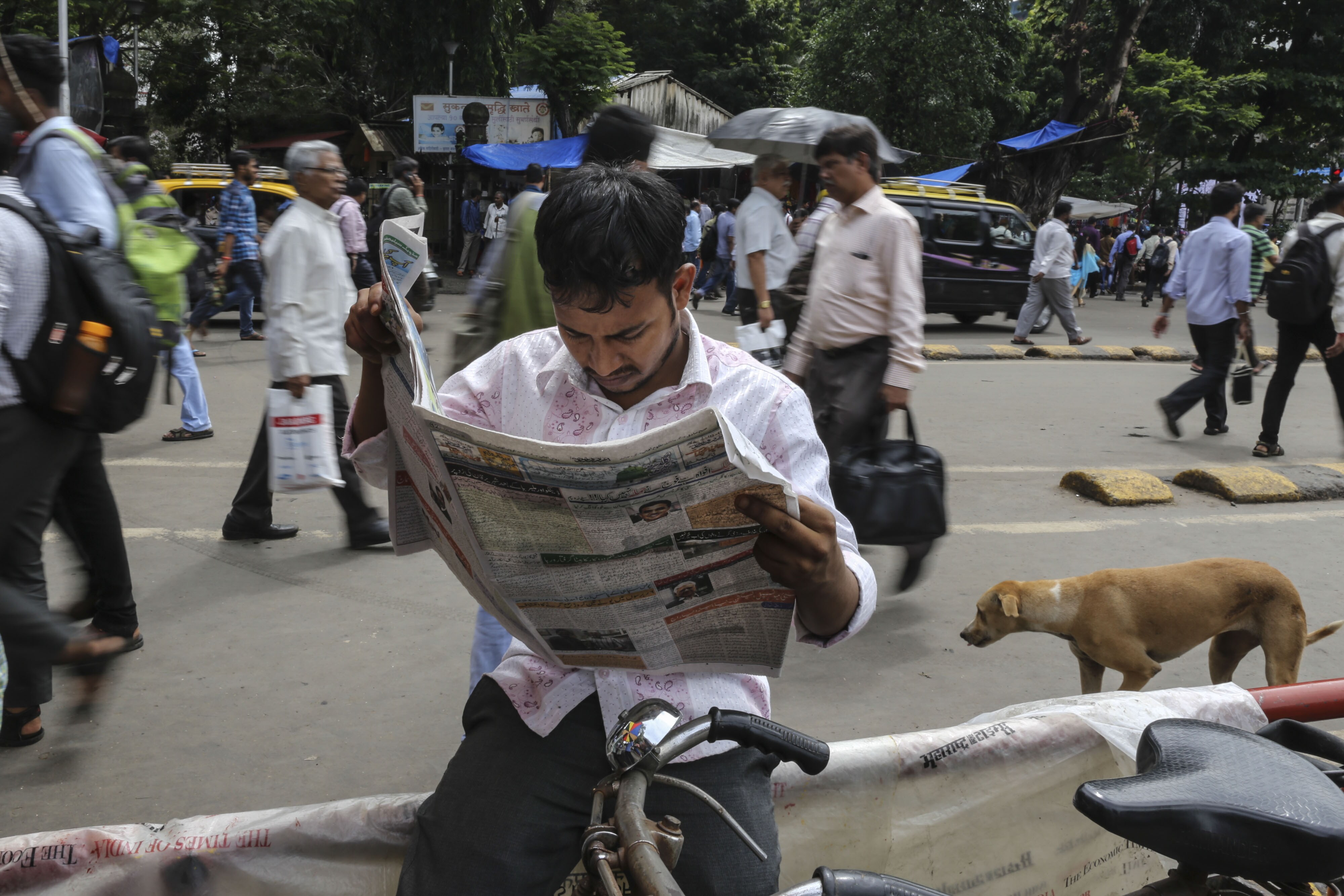 A man reads a newspaper outside Chhatrapati Shivaji Terminal in Mumbai, India, on October 5, 2016. (Photographer: Dhiraj Singh/Bloomberg)