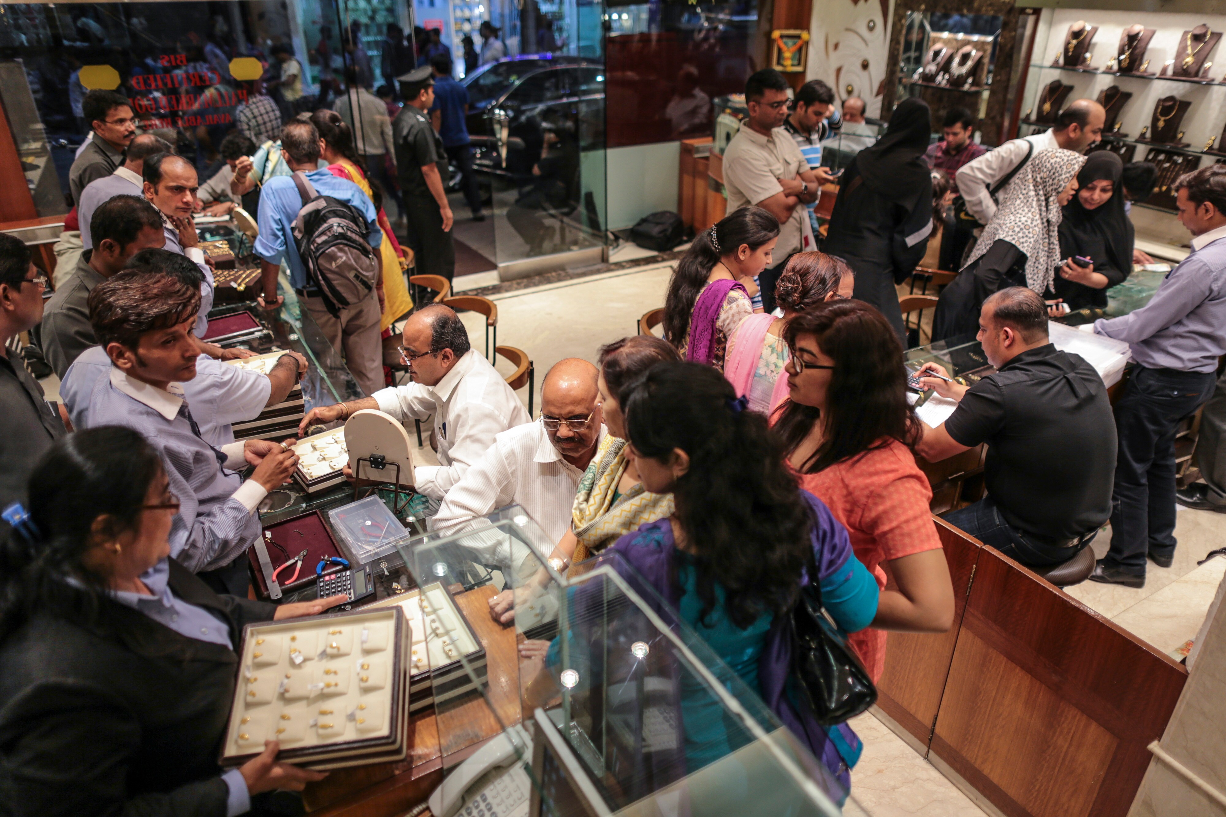 Customers shop for jewelry inside the Dwarkadas Chandumal Jewelers store in the Zaveri Bazaar area of Mumbai, India, to celebrate the Akshaya Tritiya festival on April 21, 2015. (Photographer: Dhiraj Singh/Bloomberg)