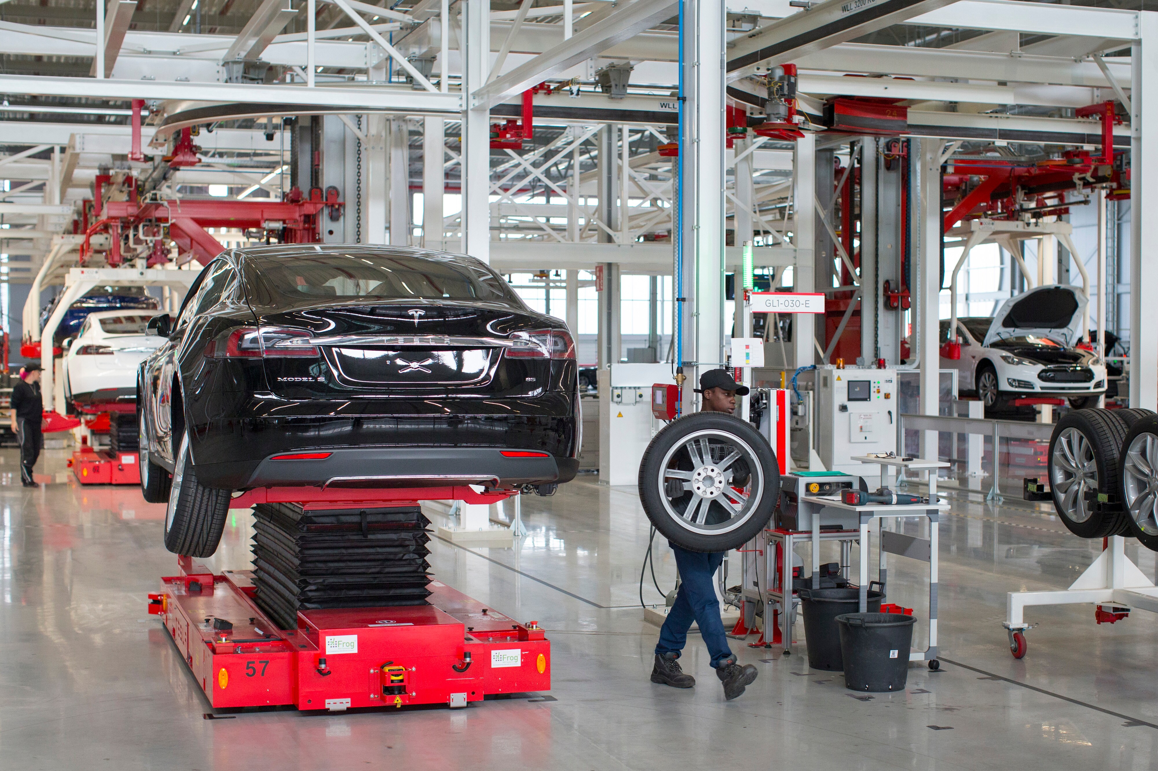 An employee removes a wheel from a Tesla Model S automobile during driving unit fitting on the final assembly line at the Tesla Motors Inc. factory in Tilburg, Netherlands. (Photographer: Jasper Juinen/Bloomberg)