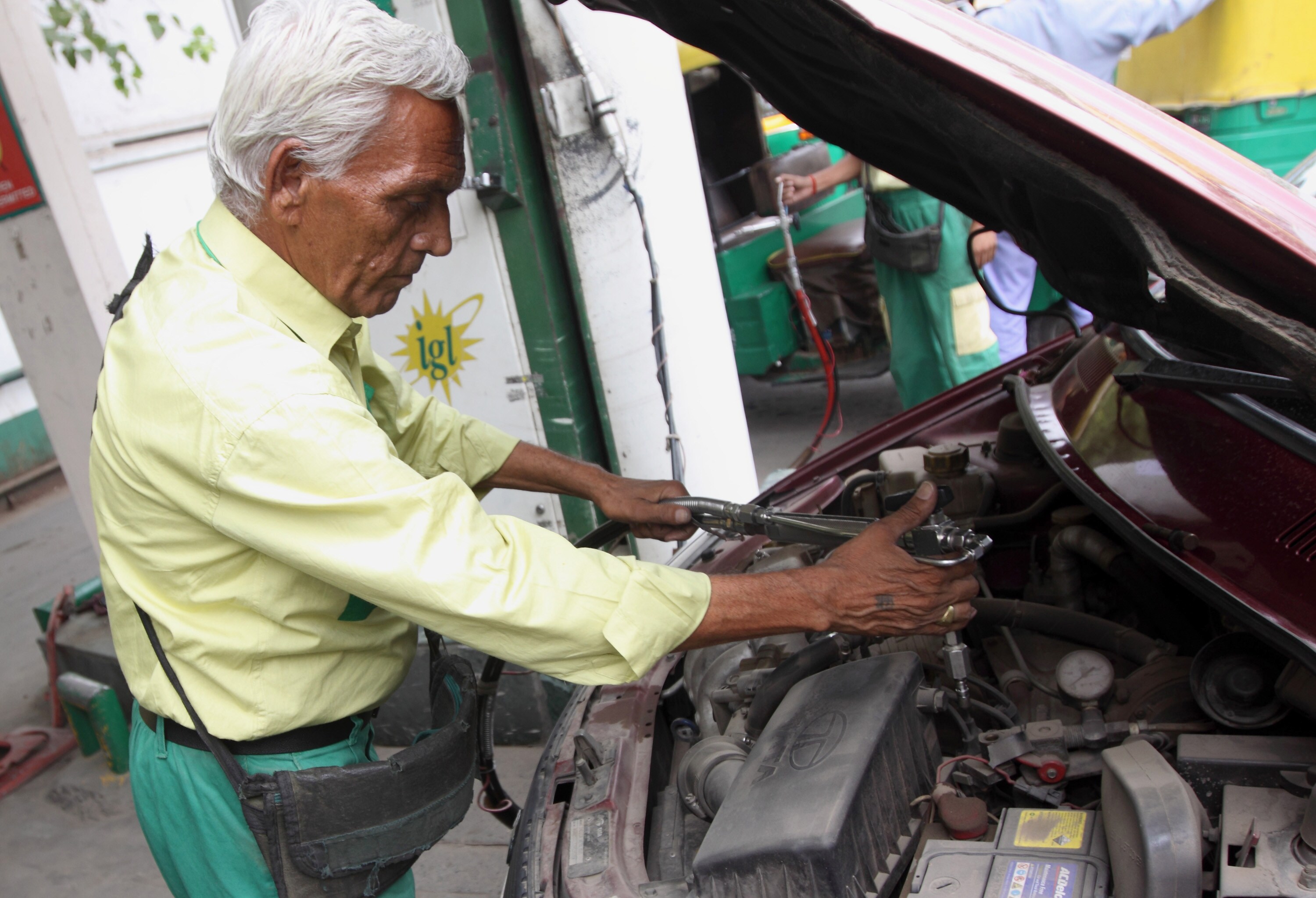An Indraprastha Gas Ltd. attendant fills up a customer's car with compressed natural gas (CNG) at a station in New Delhi, India (Photographer: Pankaj Nangia/Bloomberg)