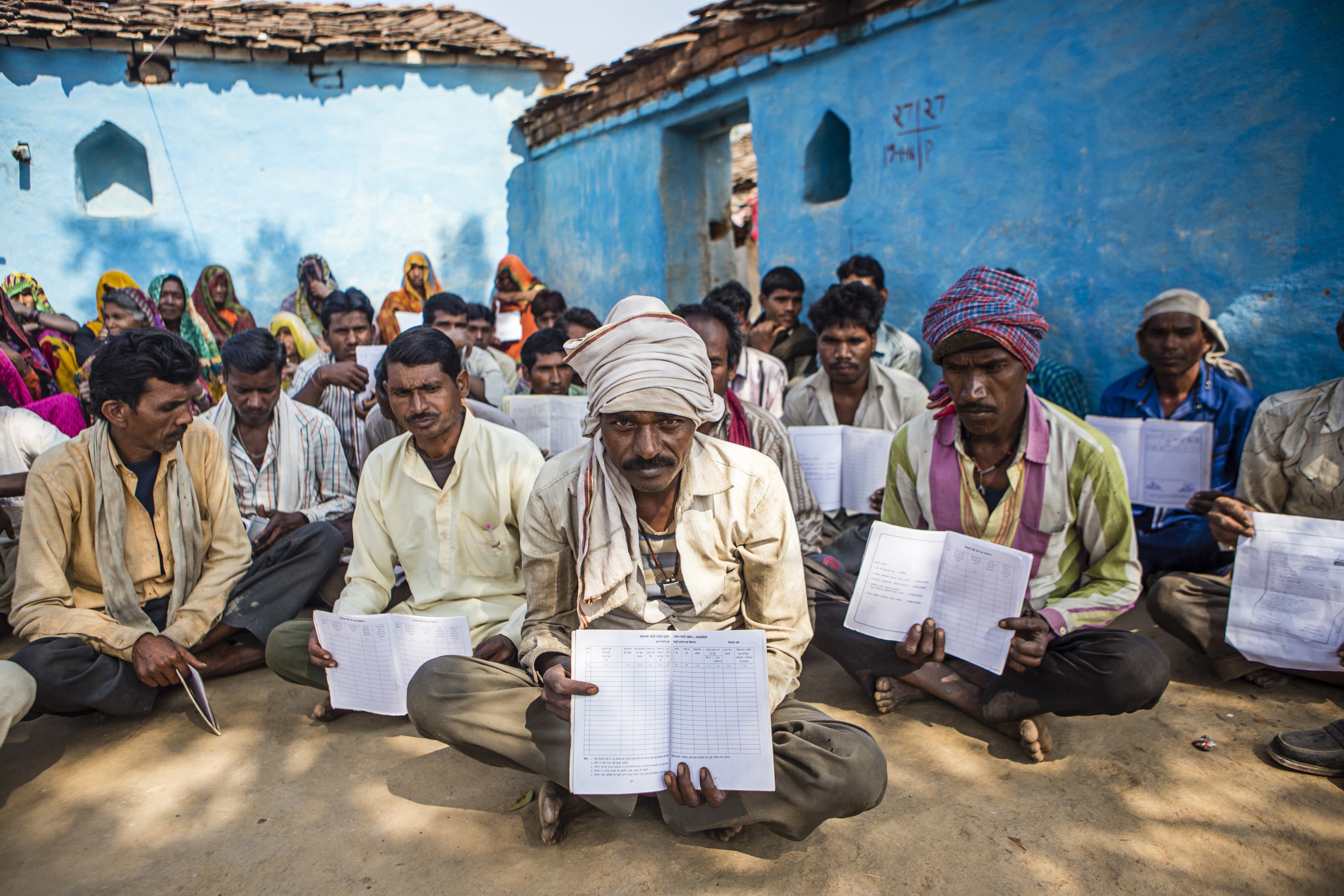 Villagers hold up their job cards with no entries for the rural jobs program, during a public hearing in the village of Lar Sauryana in Tikamgarh, Madhya Pradesh, India. (Photographer: Prashanth Vishwanathan/Bloomberg)