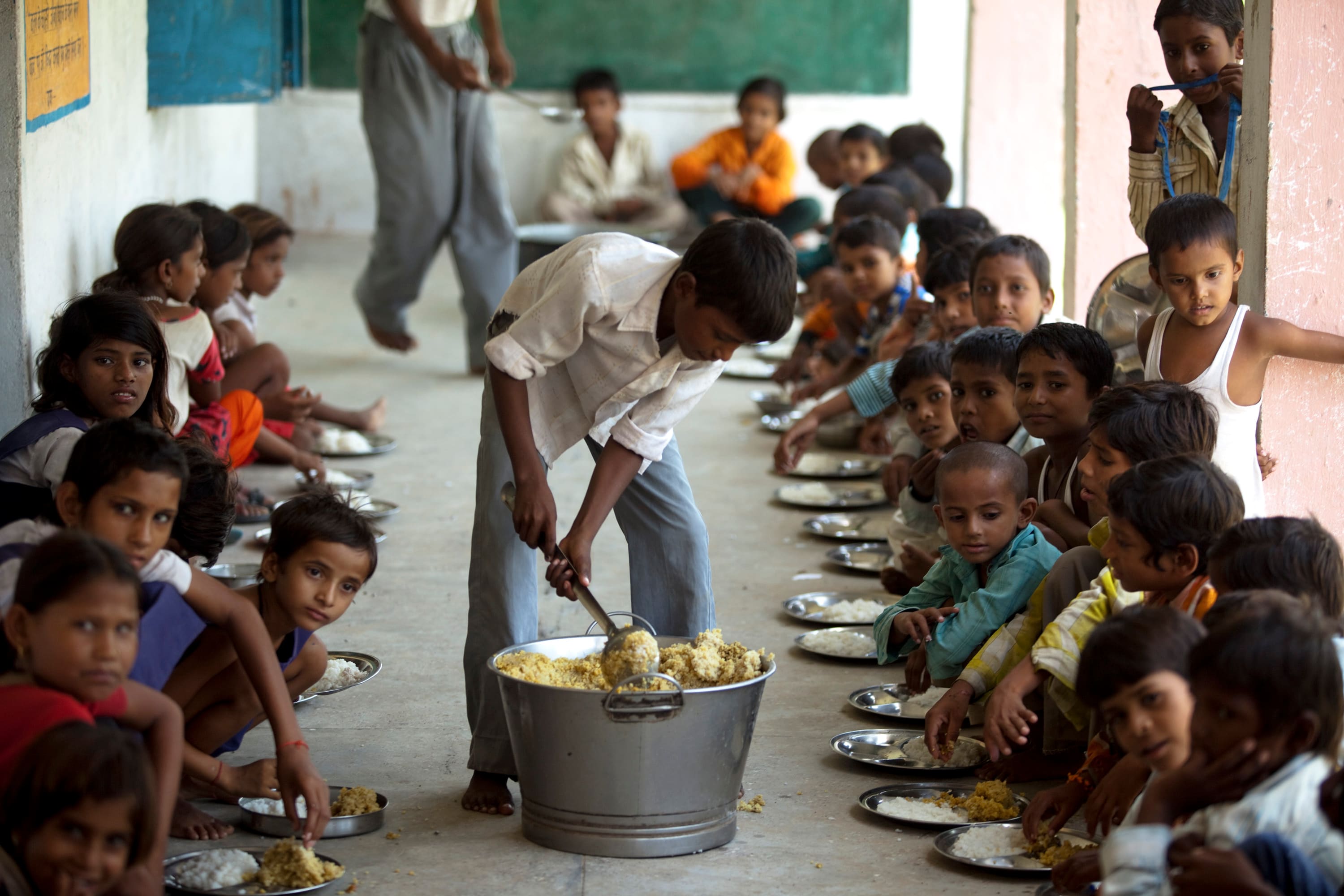 Children eat at school under the government run scheme of “Mid Day Meals” in Laundi, India, (Photographer: Prashanth Vishwanathan/Bloomberg)