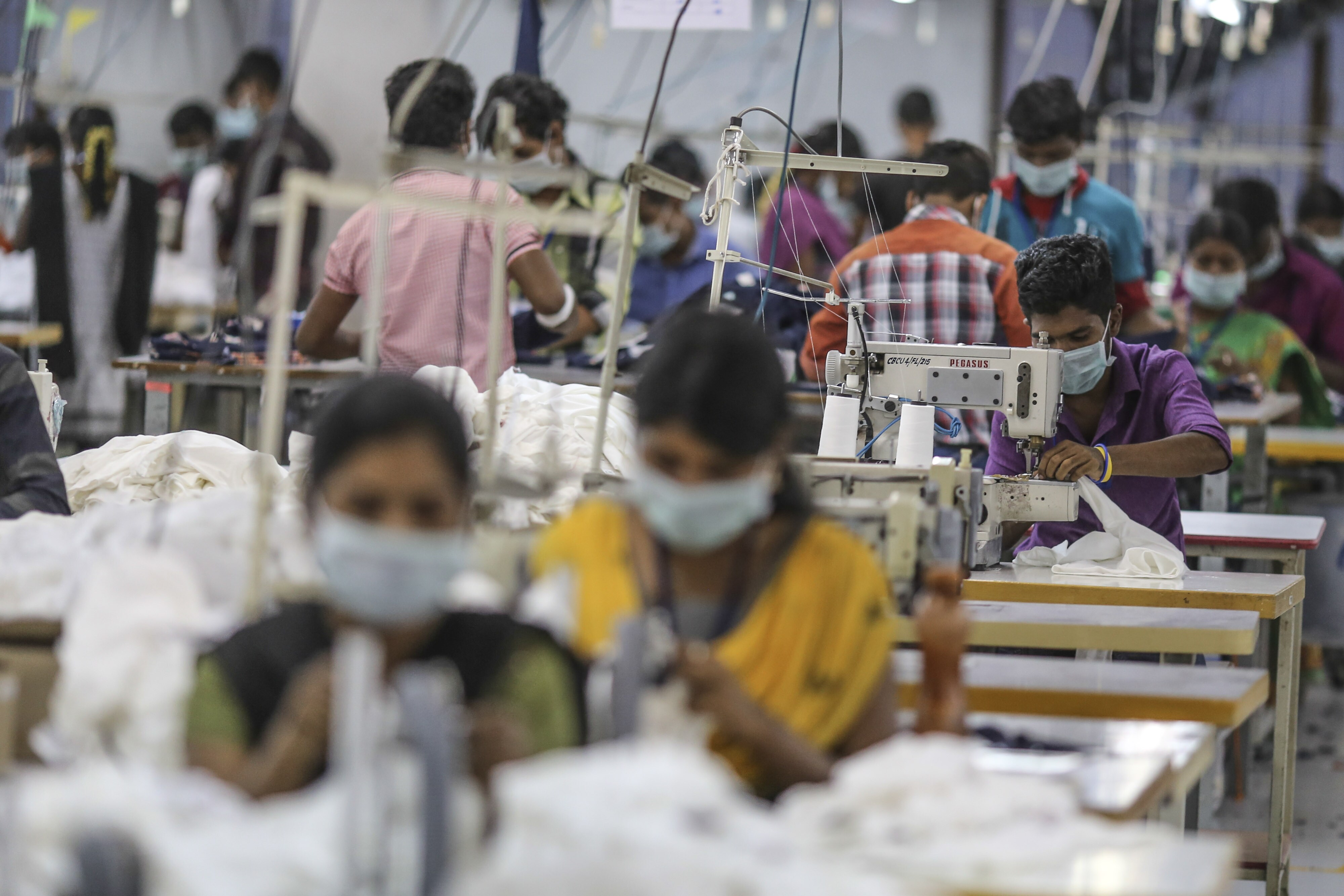 Employees use sewing machines on a production line at a factory in Tiruppur, Tamil Nadu, India. (Photographer: Dhiraj Singh/Bloomberg)