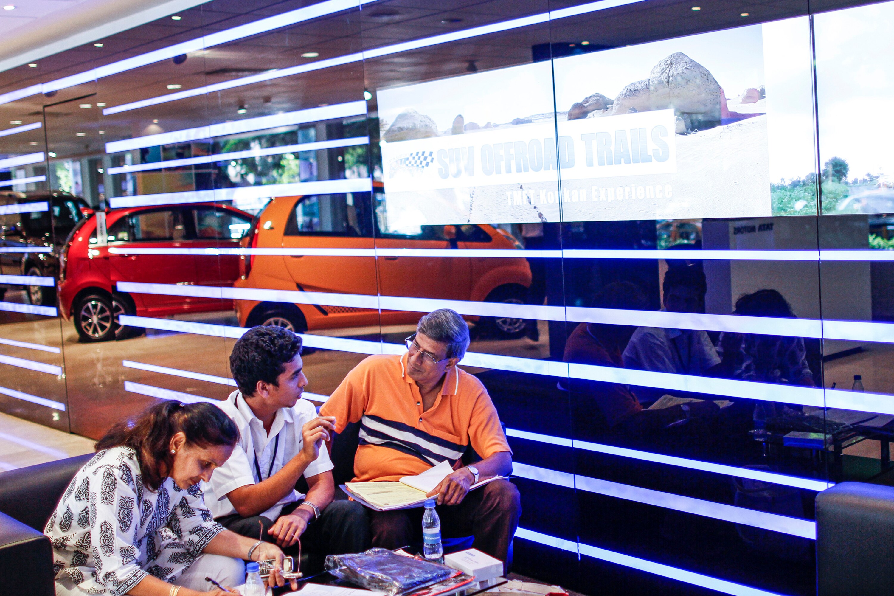 A sales person, center, sits talking with customers inside the Prabhadevi Concorde Motors India. (Photographer: Dhiraj Singh/Bloomberg)