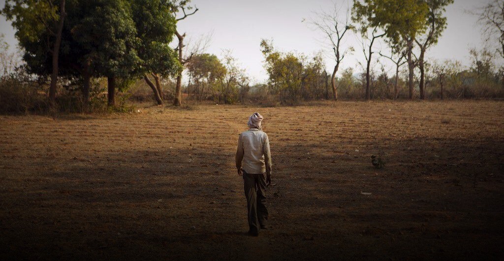 A farmer walks through his dried-up field (Photographer: Prashanth Vishwanathan/Bloomberg)
