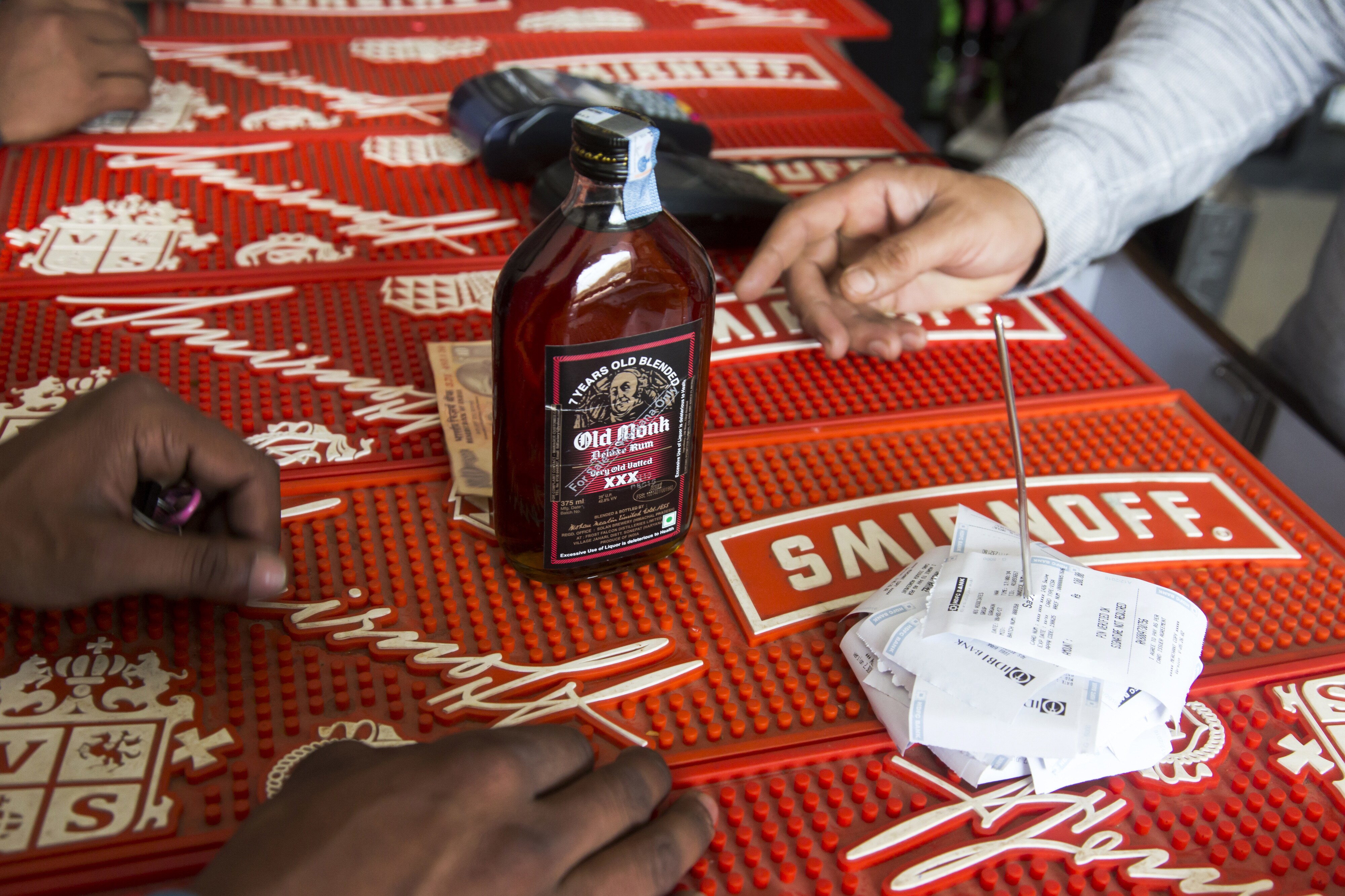 A customer purchases a bottle of Old Monk rum at a roadside liquor store in Gurgaon, Haryana. (Photographer: Udit Kulshrestha/Bloomberg)