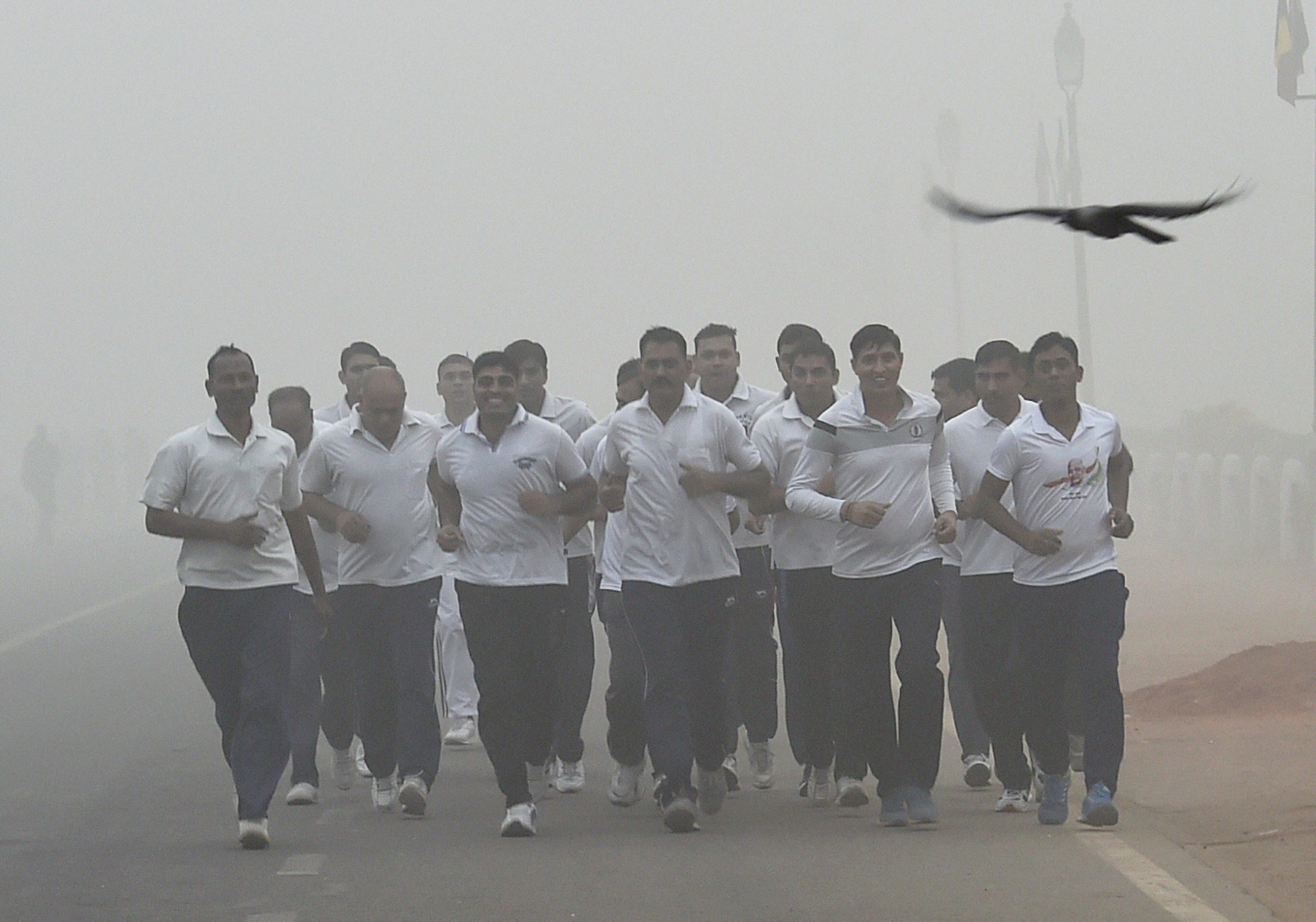 Security personnel jog through smog at Rajpath in New Delhi. (Source: PTI)