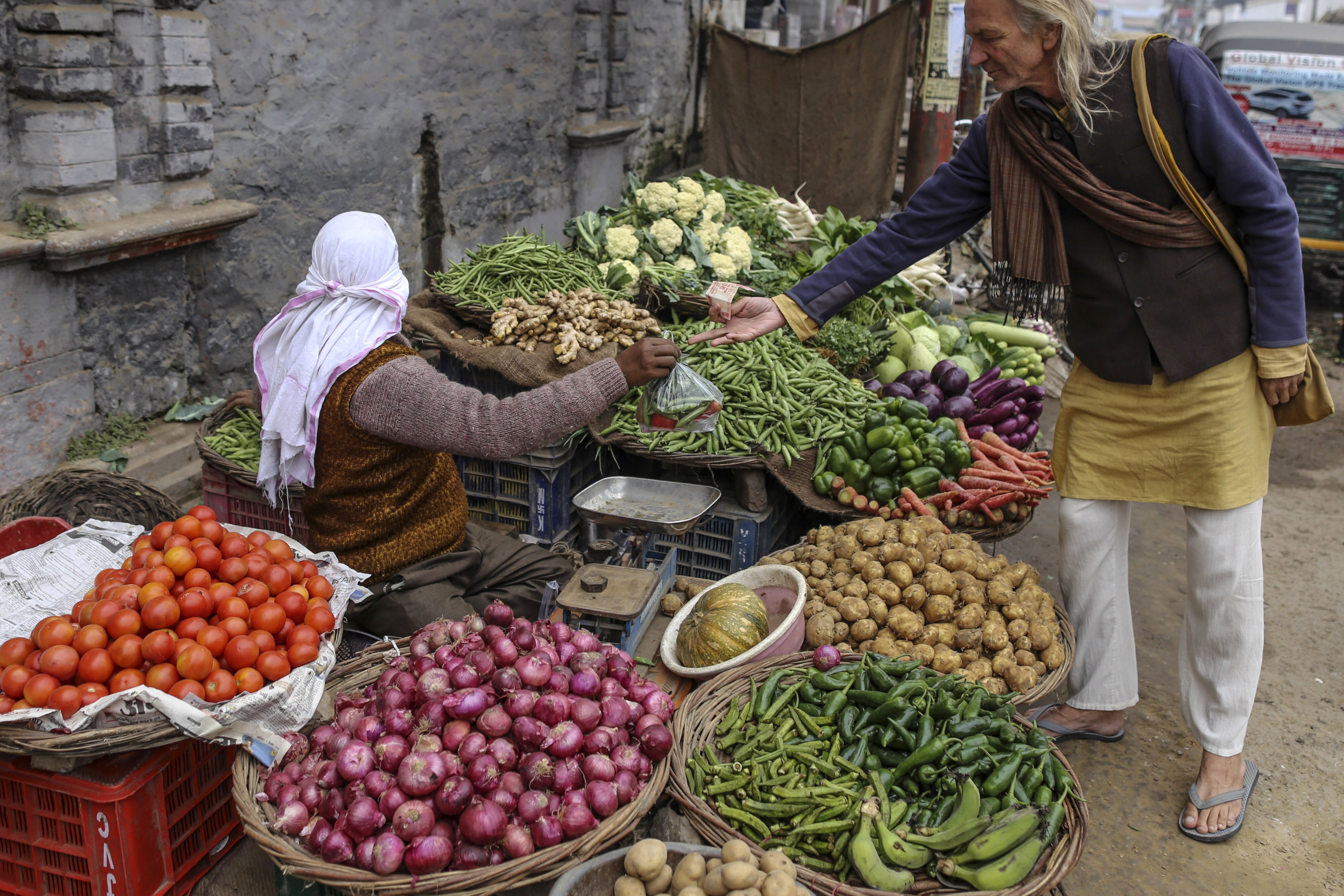 A customer pays for vegetables at a stall in Varanasi, Uttar Pradesh, India. (Photographer: Dhiraj Singh/Bloomberg)