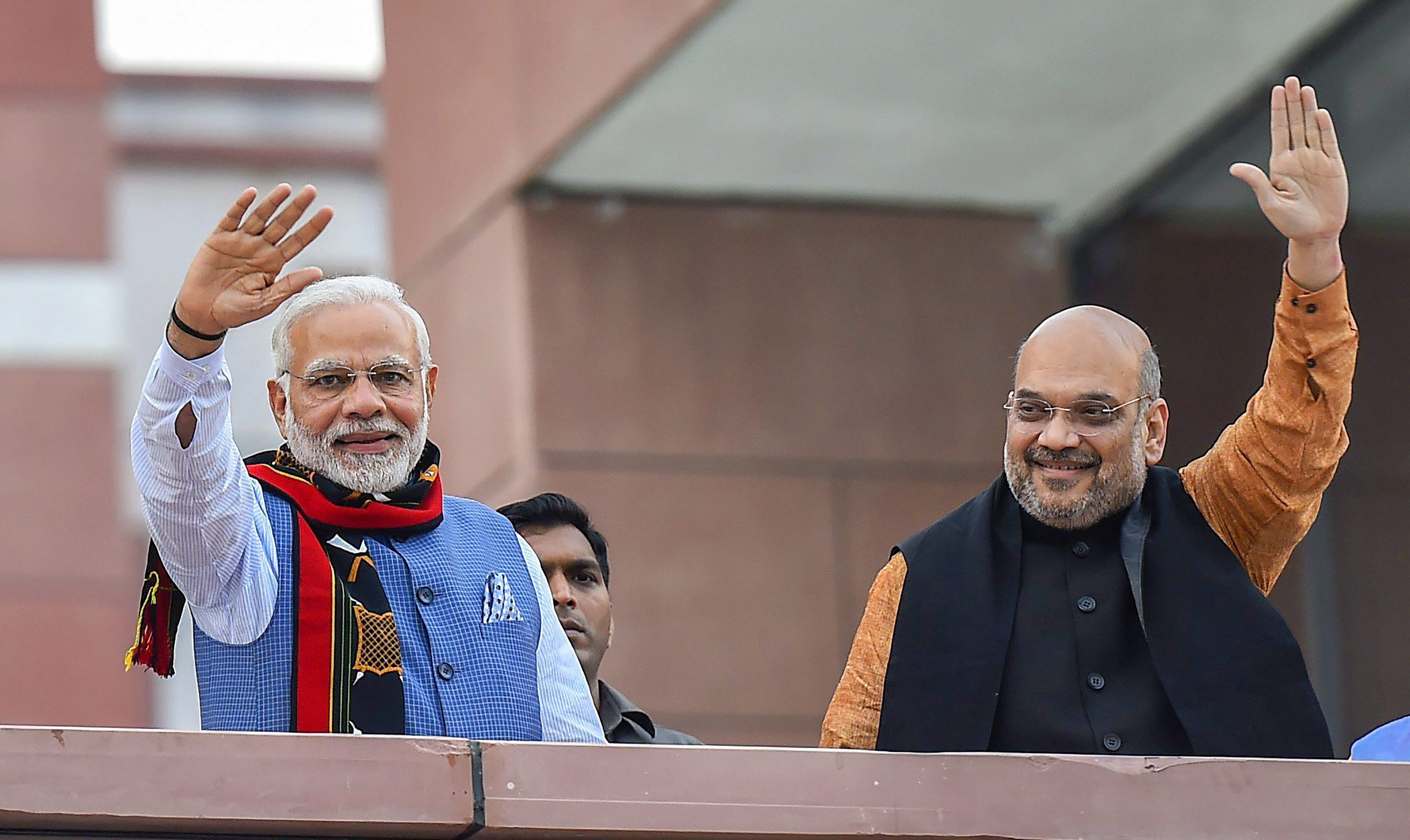 Prime Minister Narendra Modi and BJP President Amit Shah wave as they arrive to address BJP party workers after their victory in North-East Assembly election at party headquarters in New Delhi. (Image: PTI)