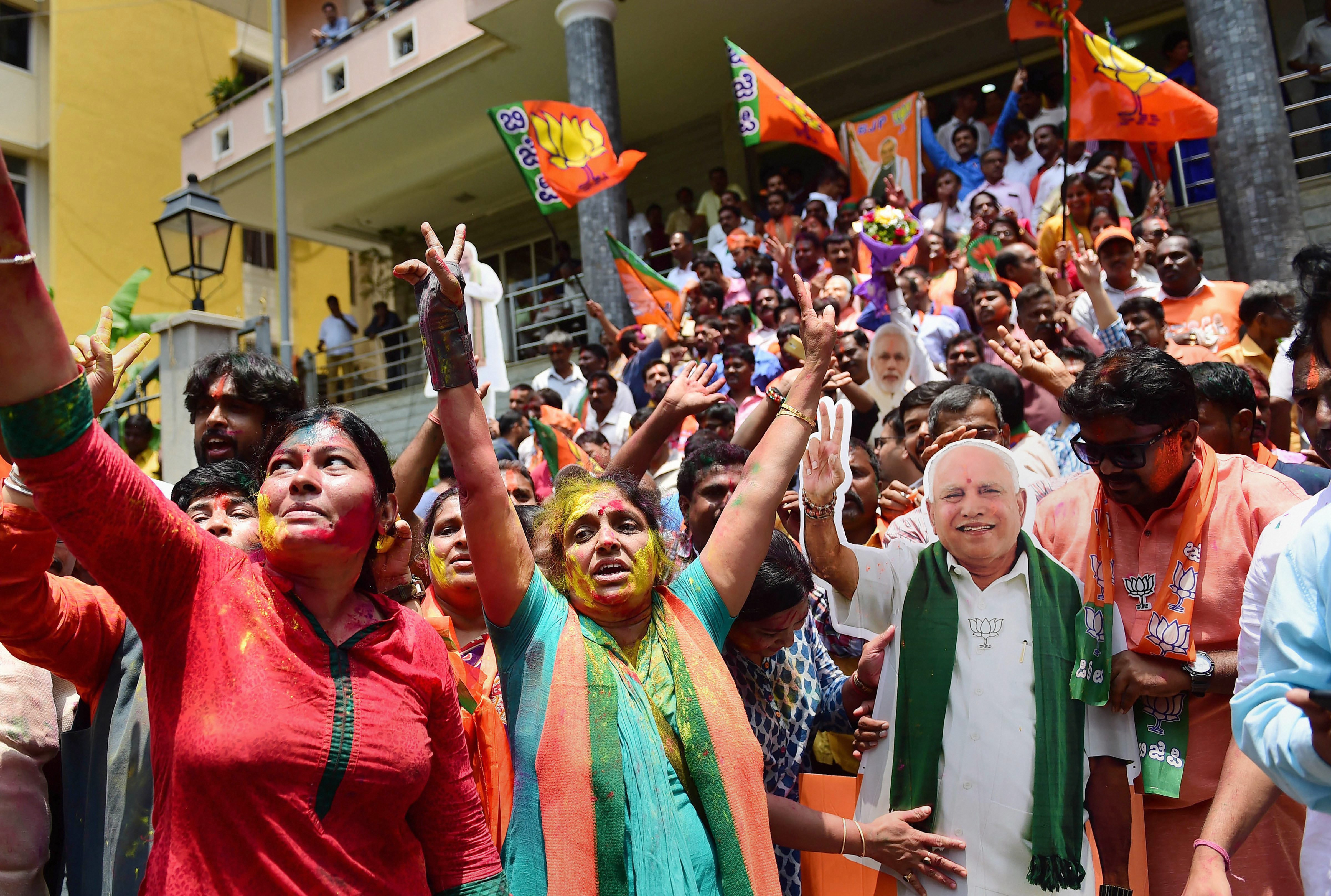 BJP workers, with a cut-out of chief ministerial candidate BS Yeddyurappa, celebrate the party's lead on more than 110 Assembly seats, as the counting of votes is in progress, outside the party office in Bengaluru. (Source: PTI)