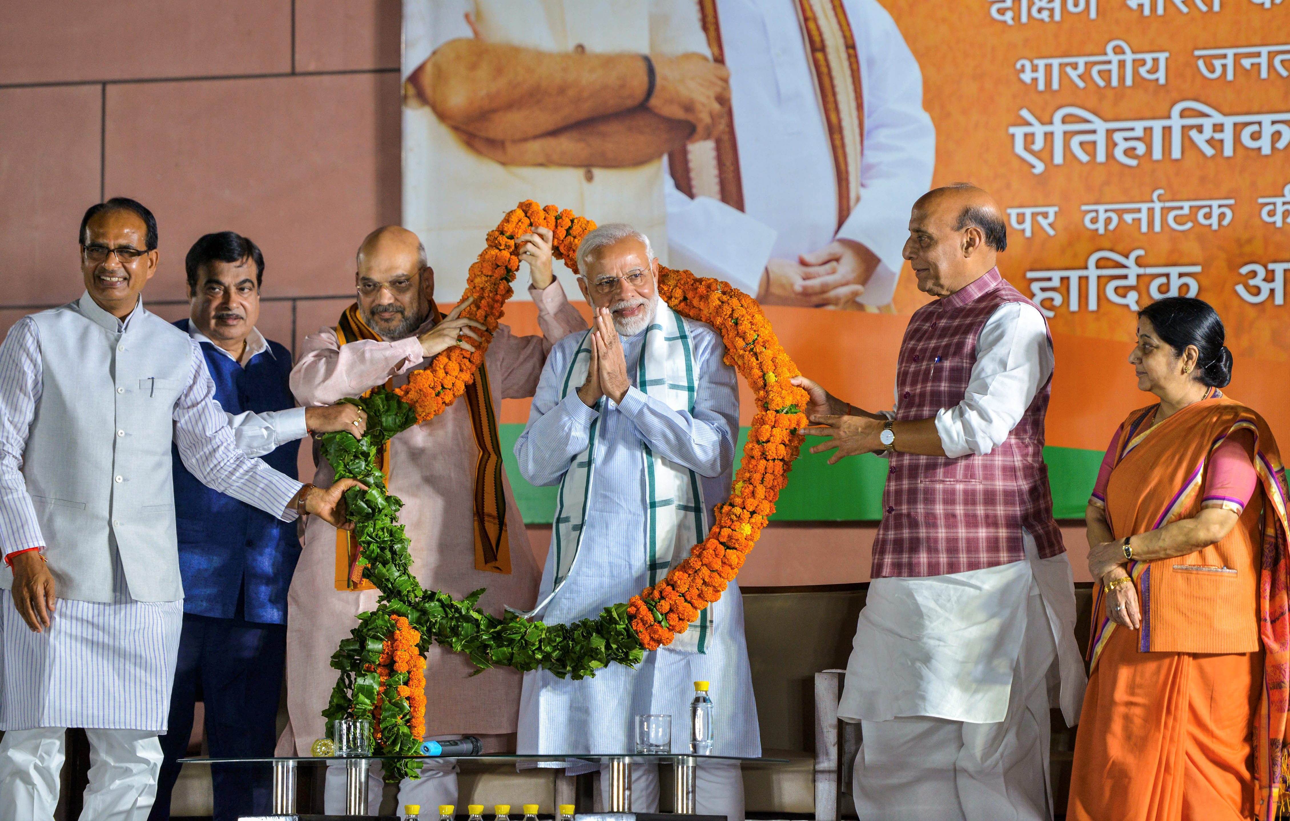BJP party workers offer milk ‘abhishek' to cut-outs of Prime Minister Narendra Modi and BJP state unit President BS Yediyurappa as they celebrate BJP's lead in Karnataka Assembly Election 2018 outside the party office in Bengaluru. (Photographer: Shailendra Bhojak/PTI)