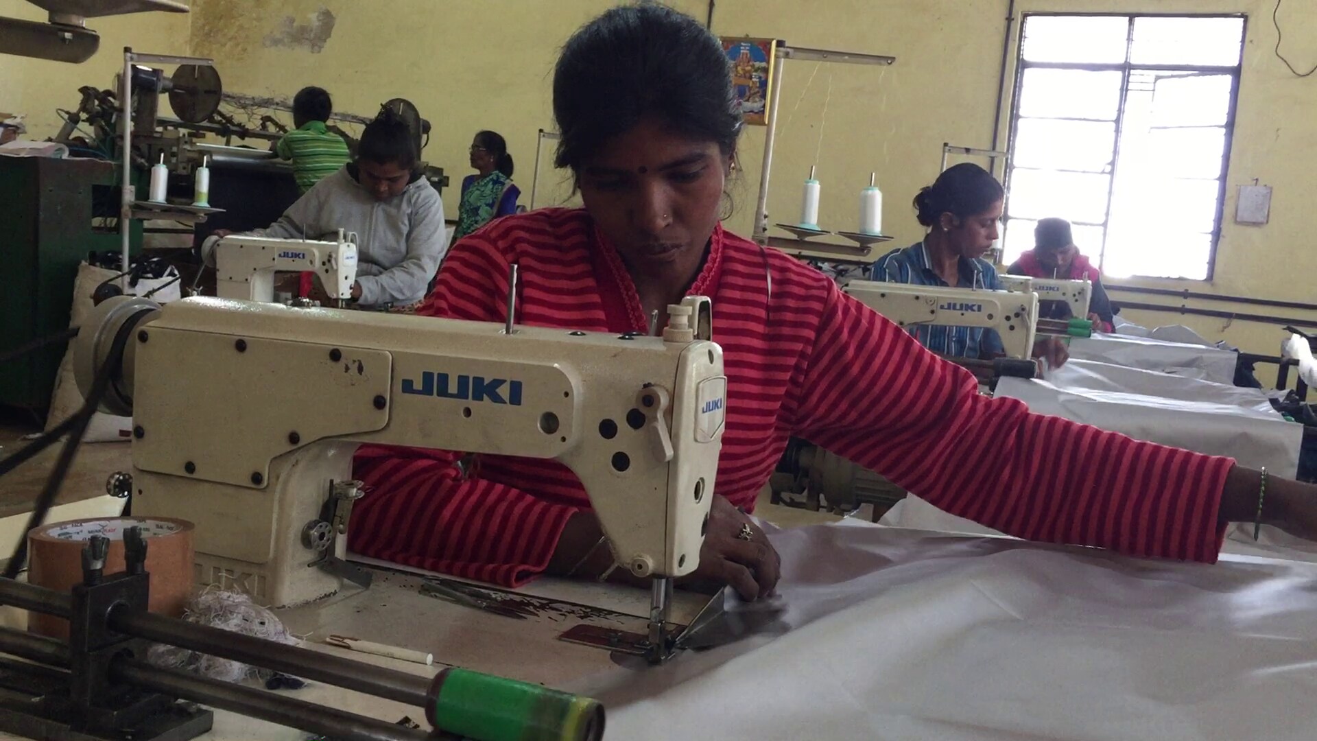 Women stitch canvas sheets into umbrellas at a unit run by Sun Umbrellas in Mysuru. (Photo: BloombergQuint)