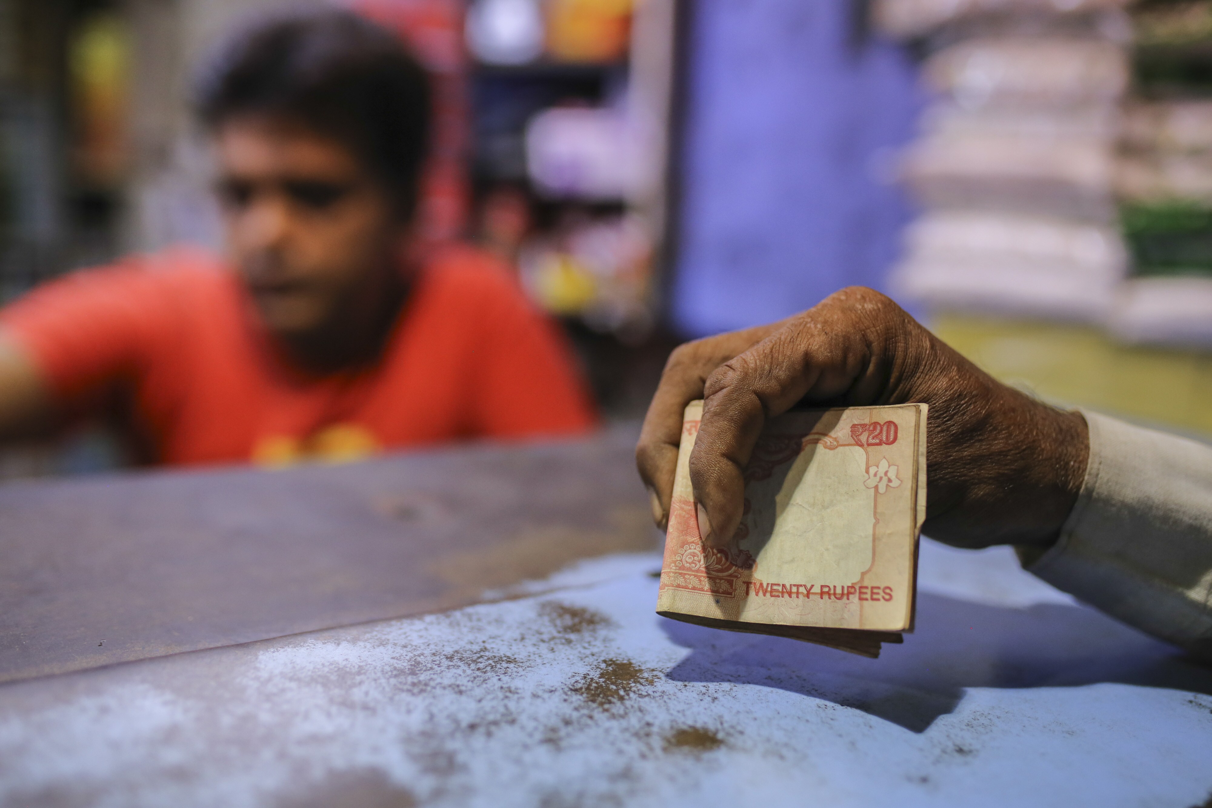 A man holds Indian twenty rupee bank notes at a shop in Mumbai, India. (Photographer: Dhiraj Singh/Bloomberg)