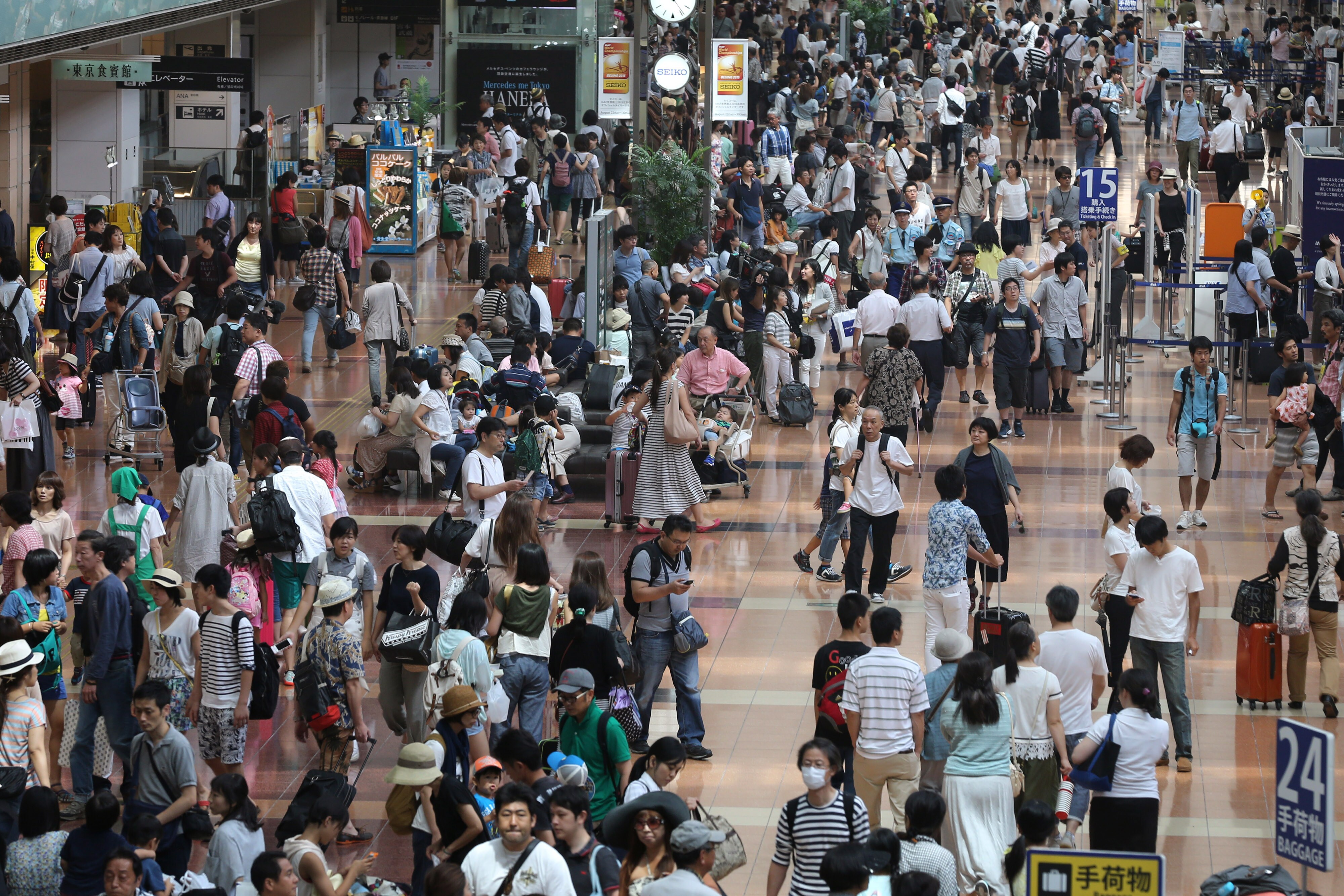Passengers walk through the departure lobby of Haneda Airport in Tokyo. (Photographer: Yuriko Nakao/Bloomberg)
