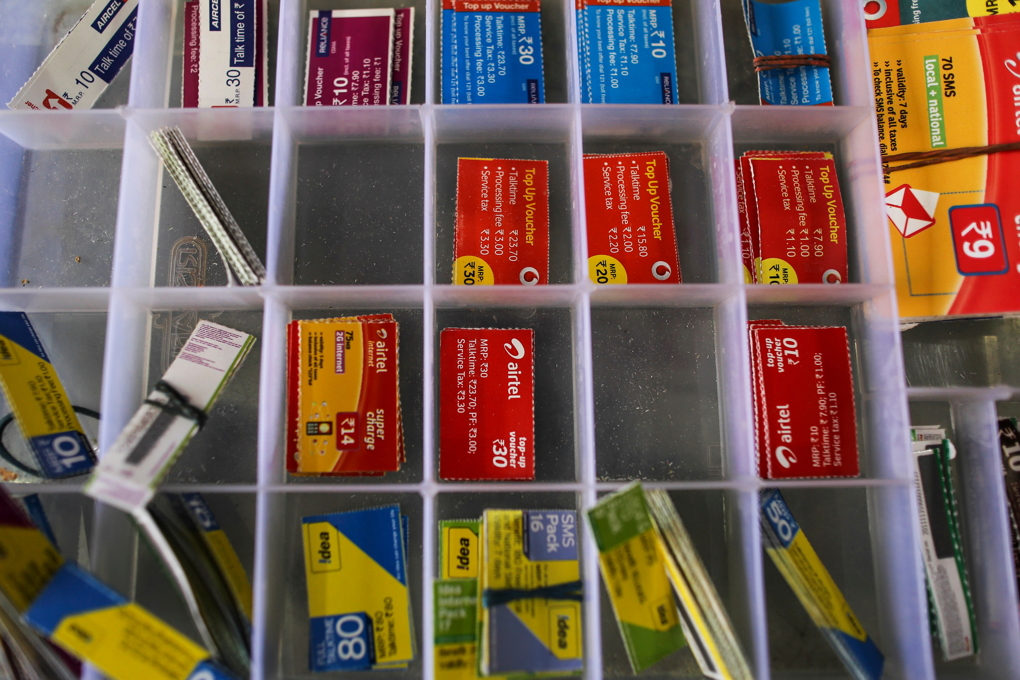 Top-up vouchers for Aircel Ltd., clockwise from top left, Reliance Communications Ltd., Vodafone Group Plc, Bharti Airtel Ltd., and Idea Cellular Ltd. sit inside a box (Photographer: Dhiraj Singh/Bloomberg)