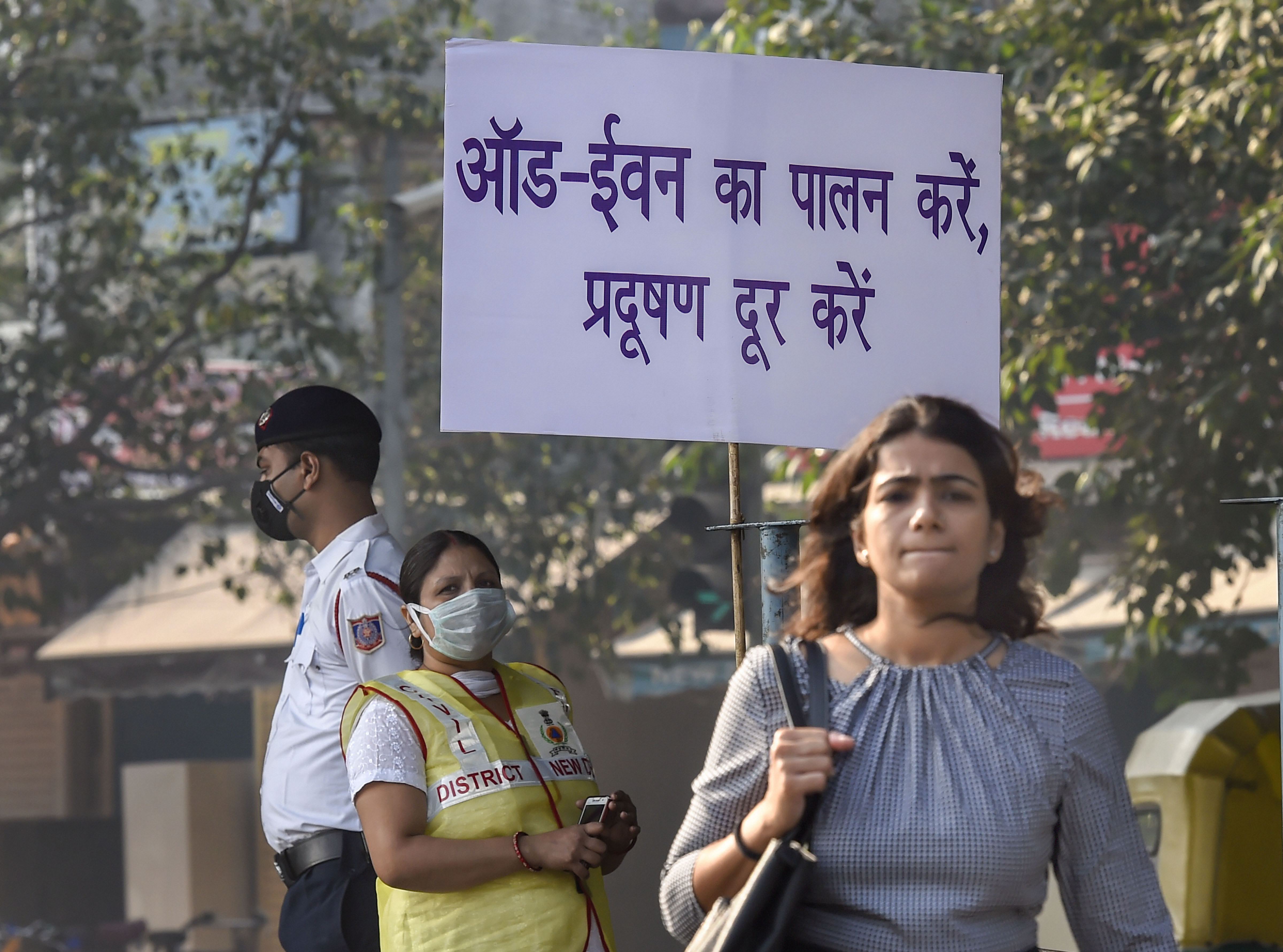 Civil Defence volunteer wearing a mask displays a placard asking people to obey the odd-even rule, in New Delhi (Source: PTI)