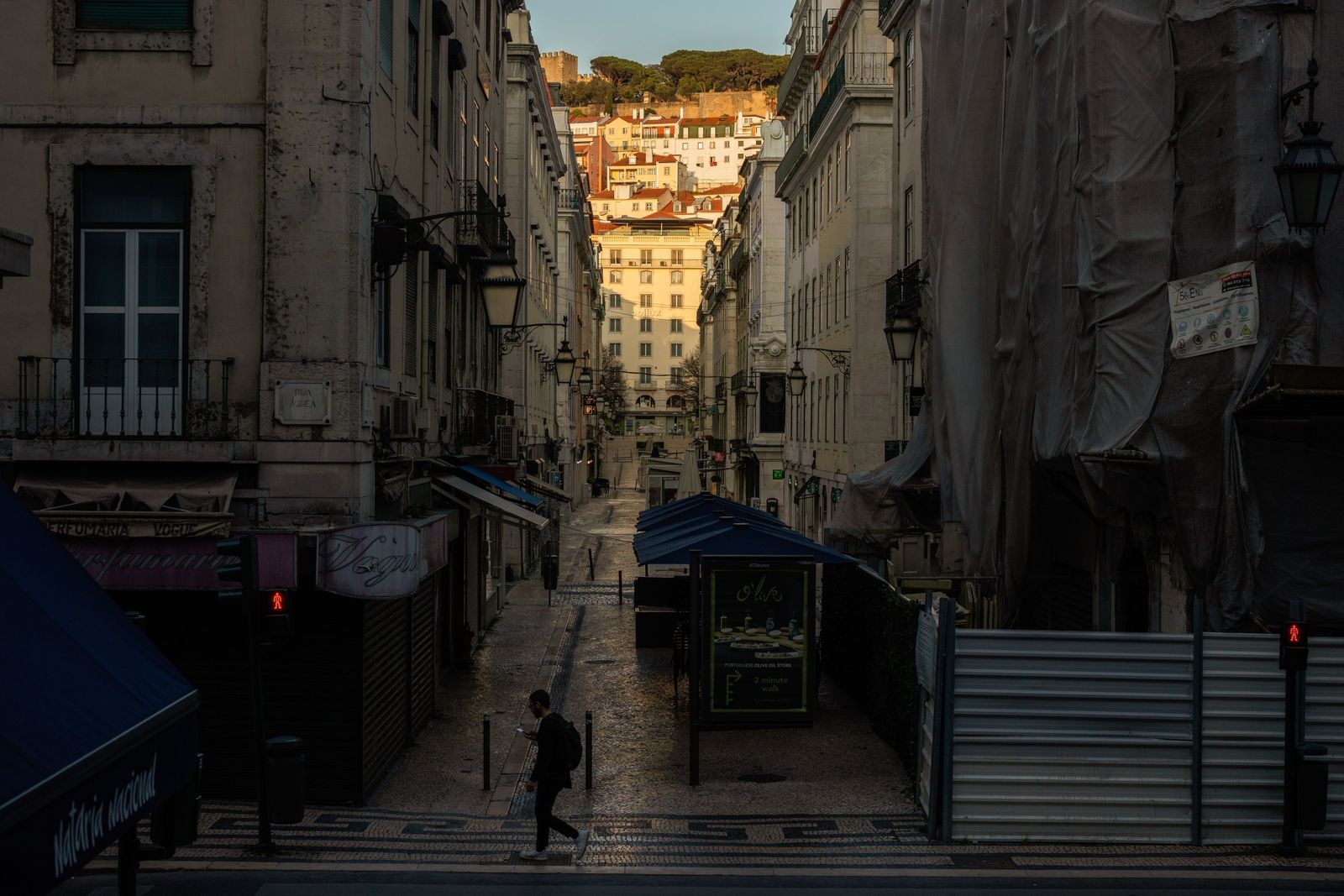 A pedestrian crosses a deserted street of usually crowded shops and cafes on March 22. (Photographer: Jose Sarmento Matos/Bloomberg)