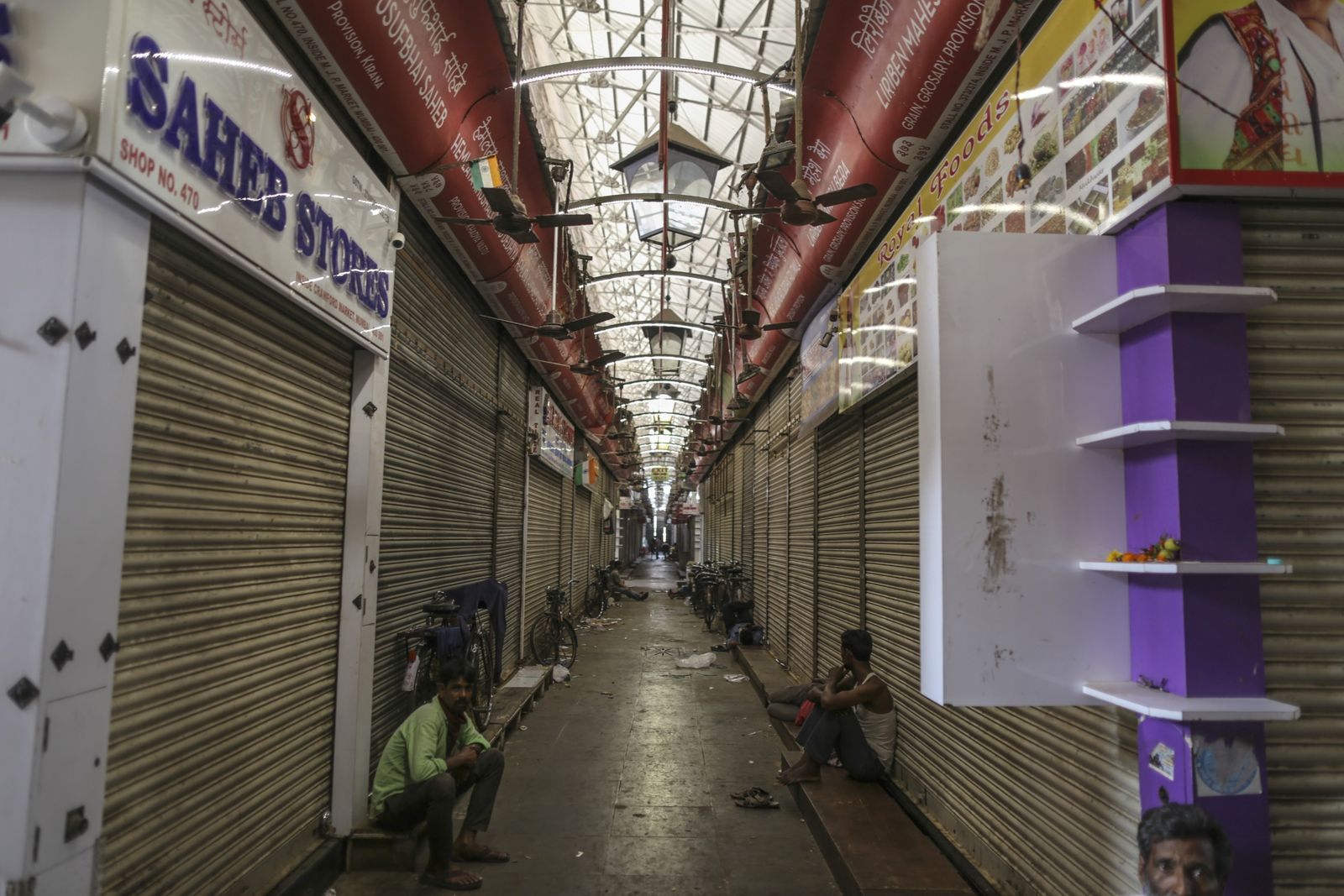 Men sit inside the closed Crawford Market on March 25. (Photographer: Dhiraj Singh/Bloomberg)