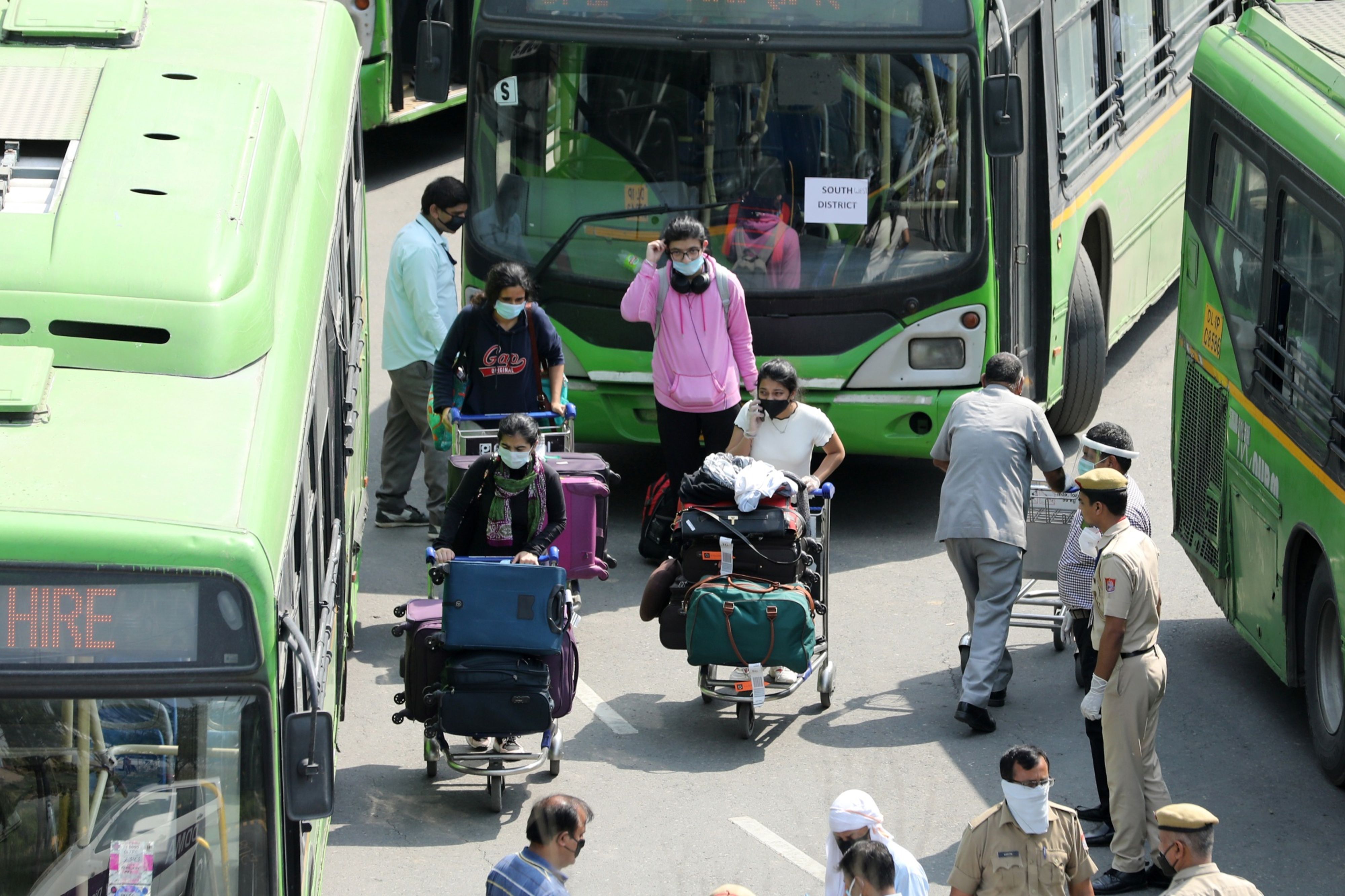 Passengers of an Air India Ltd. repatriation flight from Singapore are escorted to buses, destined for quarantine centers, at the Indira Gandhi International Airport in New Delhi, India. (Photographer: T. Narayan/Bloomberg)