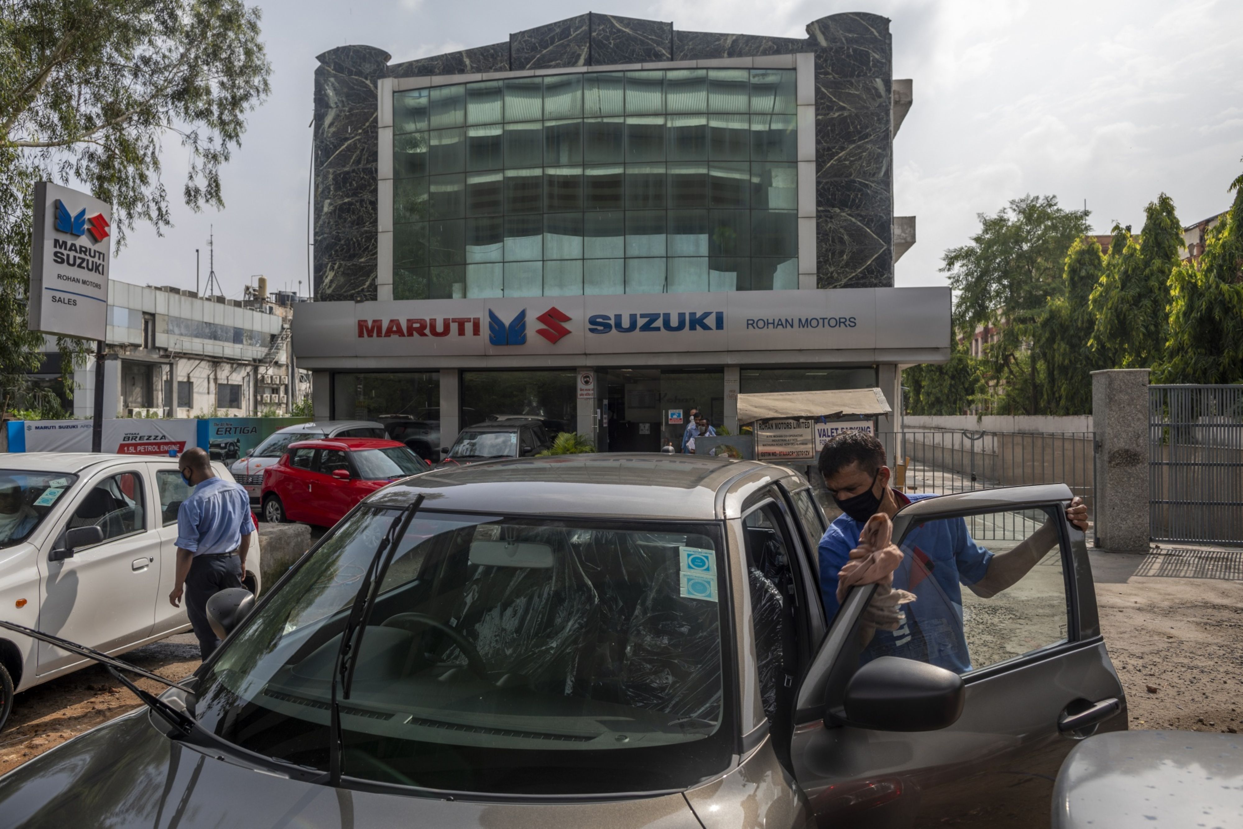 A worker cleans a Suzuki Motor Corp. vehicle outside a dealership for Maruti Suzuki India Ltd. vehicles in New Delhi, India. (Photographer: Prashanth Vishwanathan/Bloomberg)