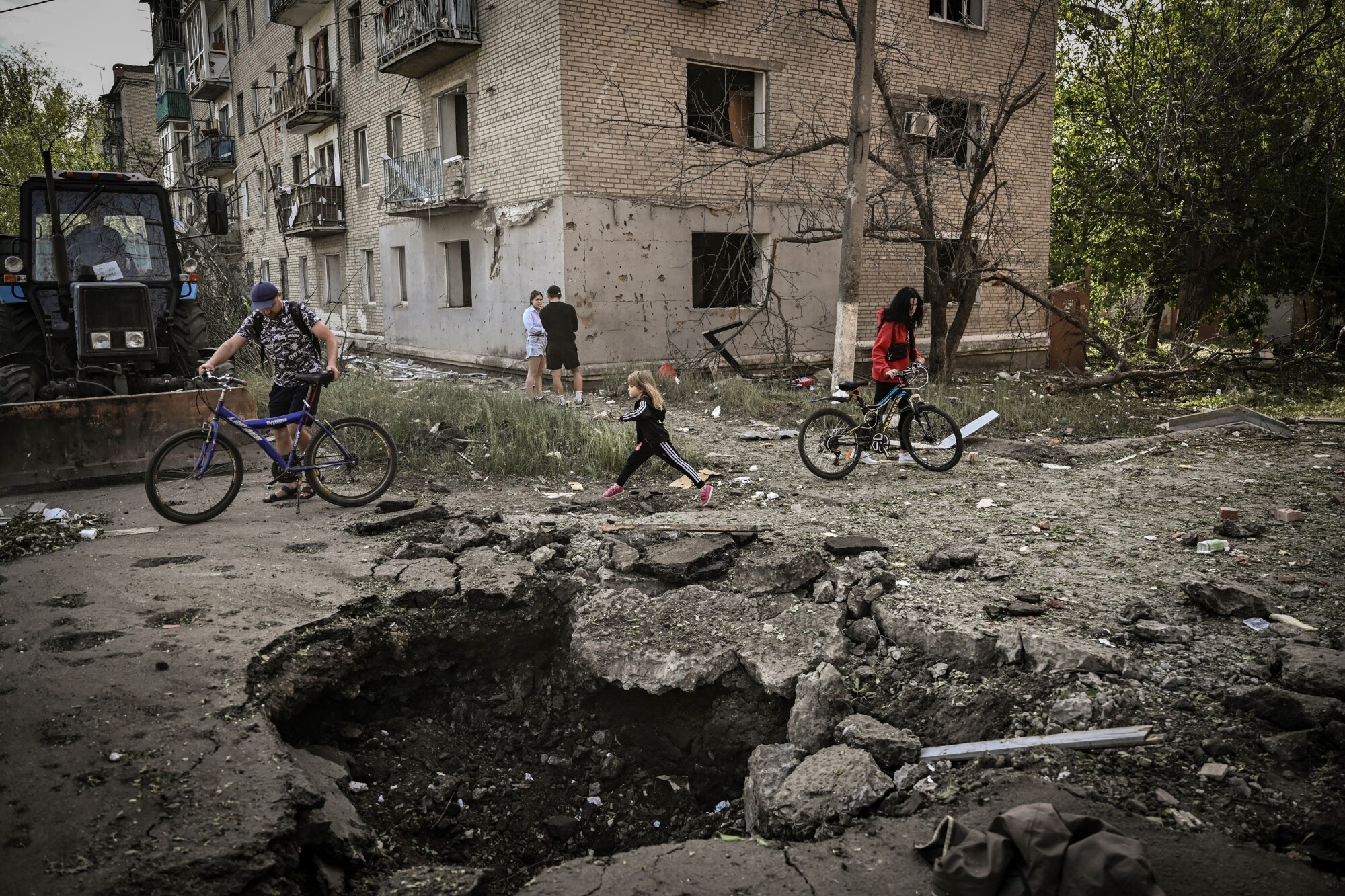 A girl walks by a crater in front of a damaged apartment building after a strike in Slovyansk, Donbas, Ukraine, on May 31.Photographer: Aris Messinis/AFP/Getty Images
