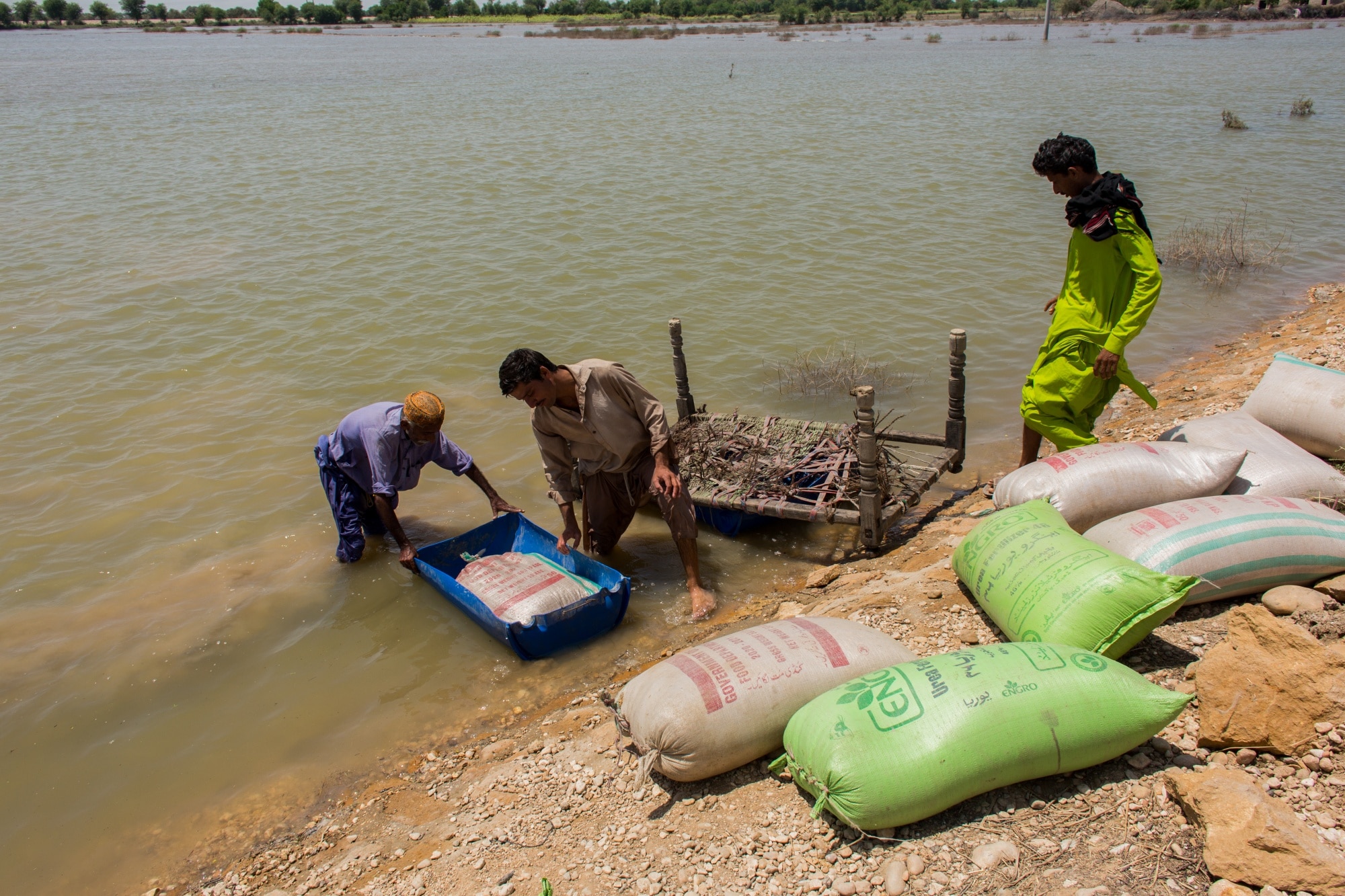 Villagers move sacks of wheat to a safer place, on Aug. 31.Photographer: Asim Hafeez/Bloomberg
