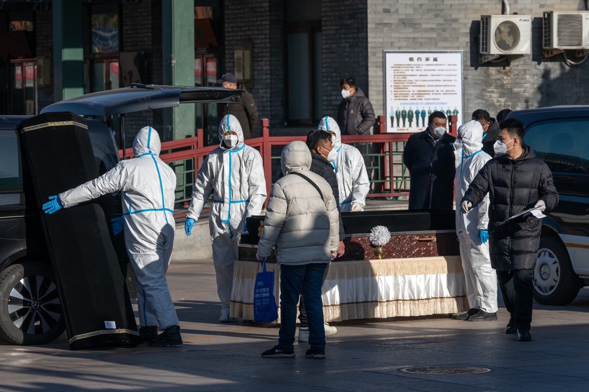 Workers in protective gear handle a coffin and coffin case at Dongjiao Funeral Parlor, reportedly designated to handle Covid fatalities, in Beijing, on Dec. 19.Source: Bloomberg