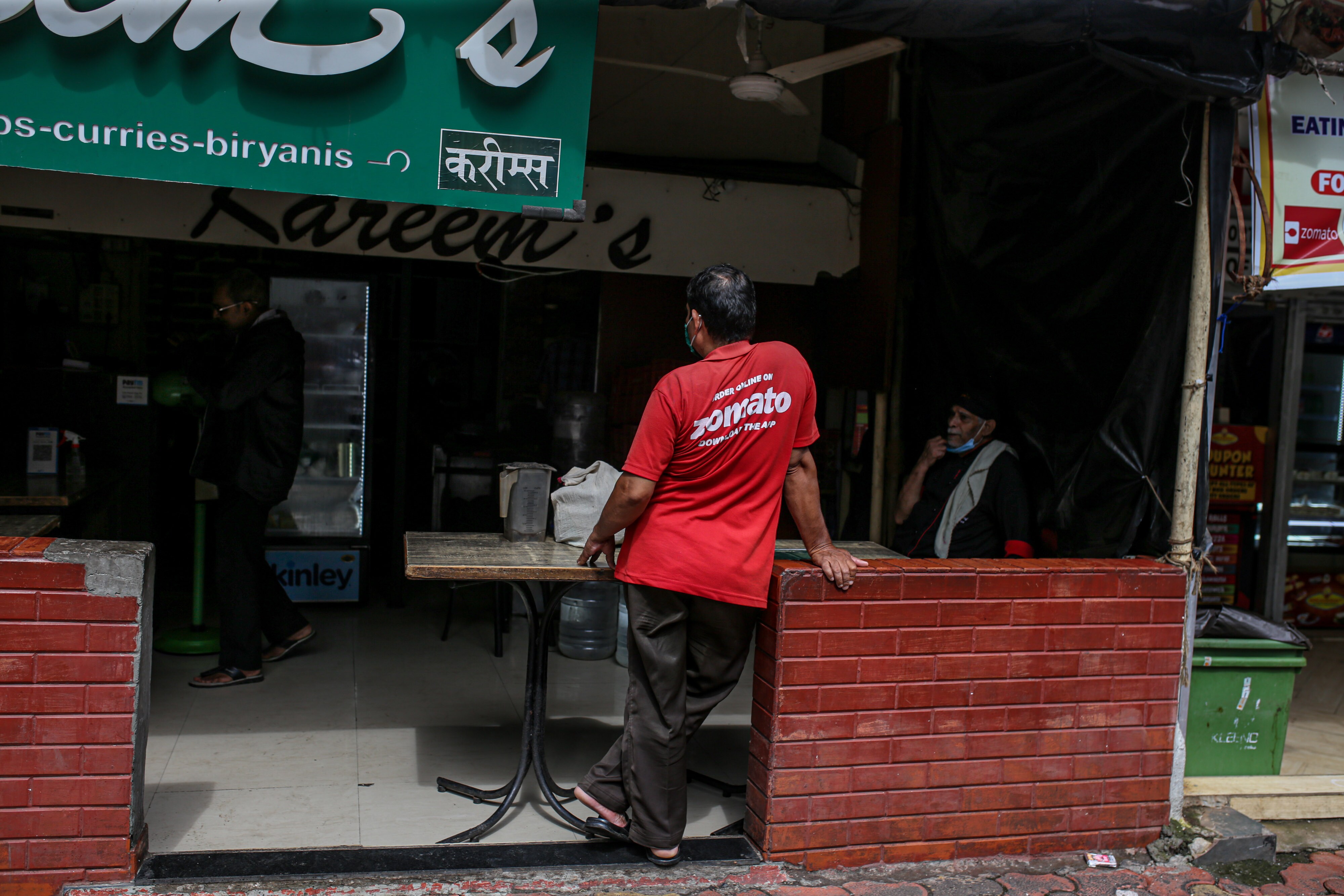A Zomato delivery rider waits to collect an order outside a restaurant in Mumbai.Photographer: Dhiraj Singh/Bloomberg