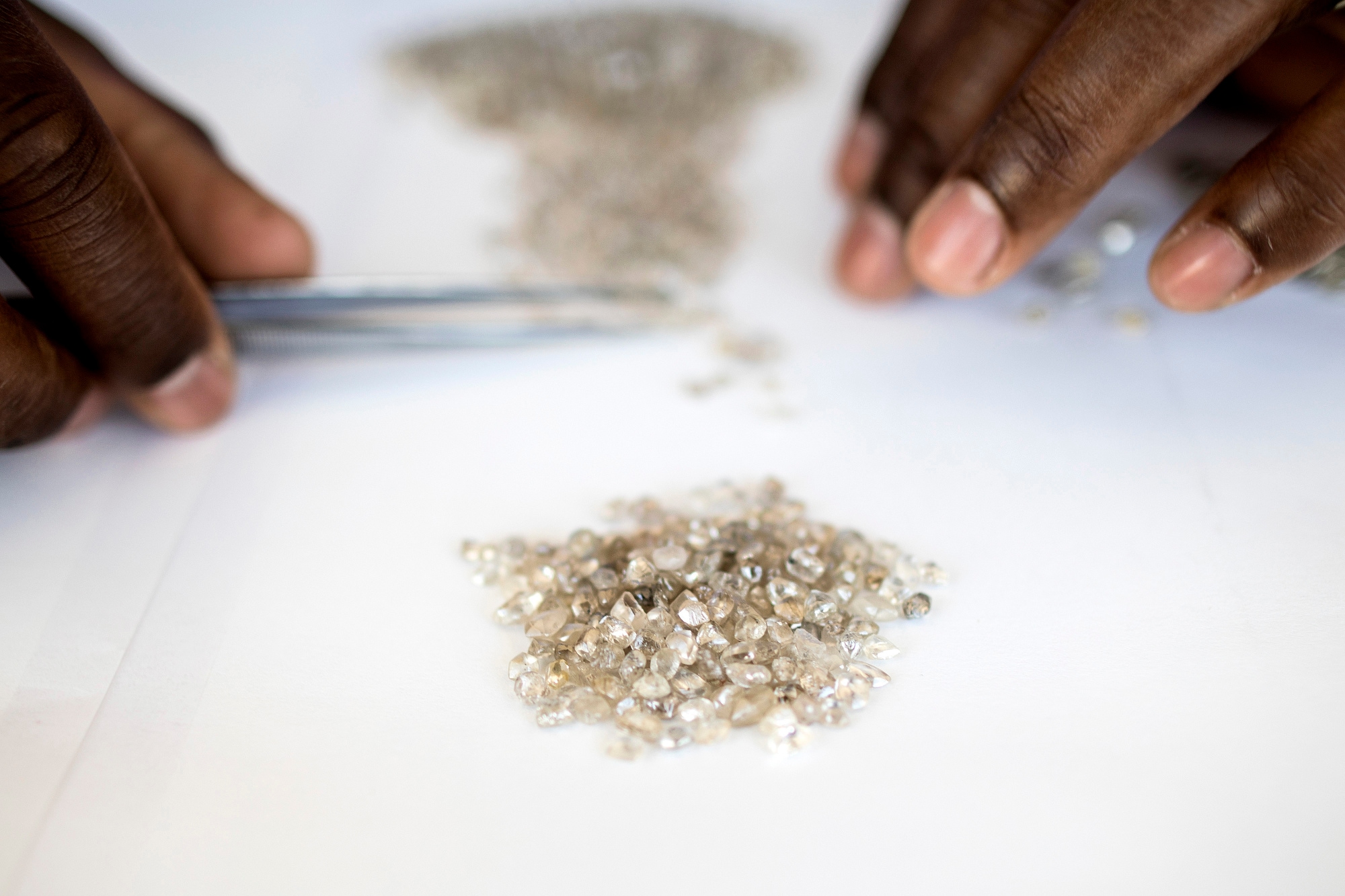 An employee grades a pile of rough diamonds at a processing and valuation center, a joint venture between De Beers Group and Namdeb Diamond Corp.Photographer: Simon Dawson/Bloomberg