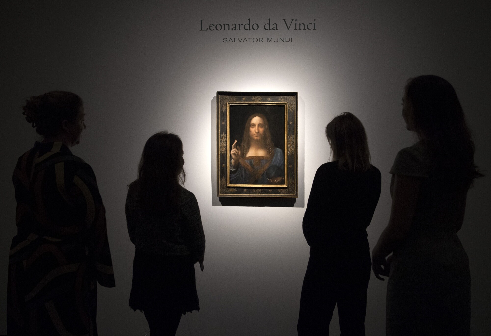 Staff members pose next to the ‘Salvator Mundi' by Leonardo di Vinci in London.Photographer: Carl Court/Getty Images